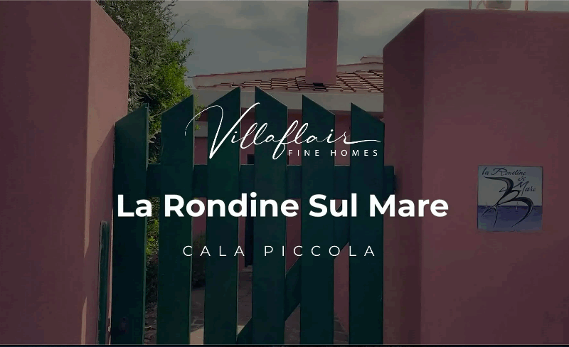 Green gate leading to "La Rondine Sul Mare" at Cala Piccola, framed by pink walls and foliage.