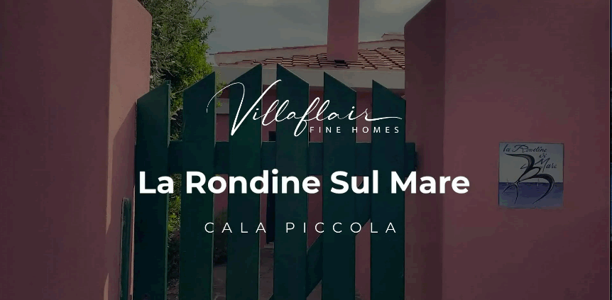 Green gate leading to "La Rondine Sul Mare" at Cala Piccola, framed by pink walls and foliage.